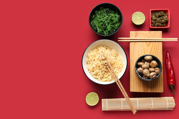 Composition with tasty Chinese dishes, bamboo mat and chopsticks on red background