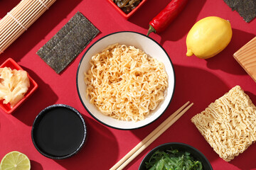 Composition with tasty Chinese dishes, chopsticks and bamboo mat on red background