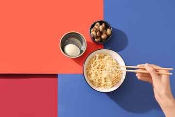 Female hand with chopsticks, bowl of tasty instant noodles, mushrooms and boiled egg on color background