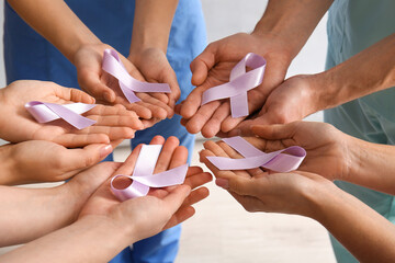 Fototapeta premium Doctors holding lilac awareness ribbons, closeup. World Cancer Day