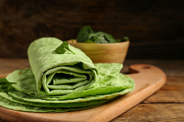 Board with fresh green lavash and spinach on wooden background