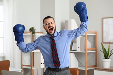 Angry businessman with boxing gloves in office. Knockout concept