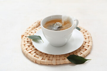 Cup of hot green tea and leaves on white background