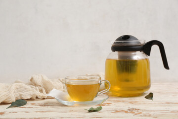 Glass cup and teapot of hot green tea on white wooden table