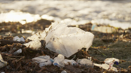 Plastic bag pollution on shoreline, sea in the background, single use waste, polluted nature