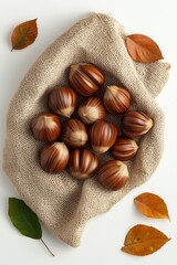 Brown chestnuts with glossy shells and dried leaves on burlap fabric background