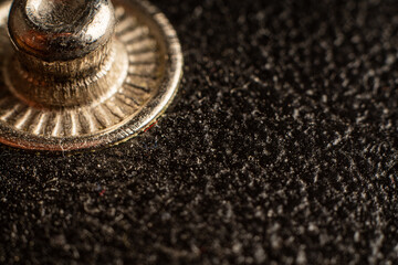 Elegant textured fabric with vintage metal button against dark background