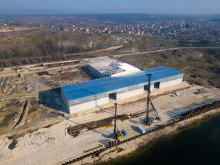A construction site with a partially built warehouse featuring a steel framework and metal roof....