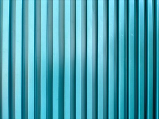 Close-up of a turquoise corrugated pvc sheet with vertical ridges, forming a repetitive industrial pattern