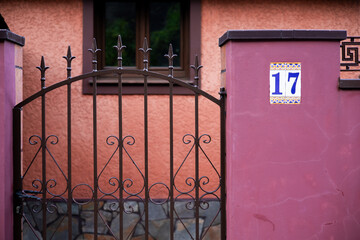 Ornate iron gate and pink wall with number 17 in spanish style architecture