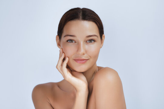 Close-up shot of a young woman with clear, glowing skin gently touching her face. Her smooth complexion and serene expression make this image ideal for beauty, skincare, and wellness campaigns.