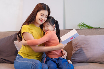 The mother warmly embraces her daughter after receiving the thoughtful handmade card, cherishing...