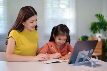 Obraz premium A mother is teaching her young daughter to do homework together at the table, creating a supportive and educational environment.