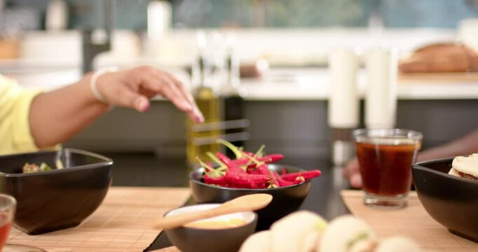 Reaching for olive oil, friends enjoying meal with tacos and drinks at table