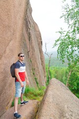 Young man is traveling among large rocks in the rocks