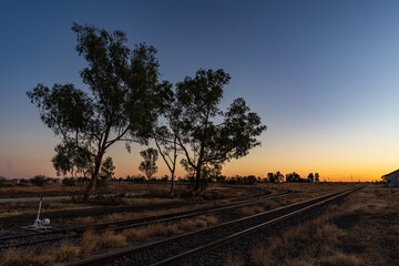 Train tracks disappearing into the distant sunrise
