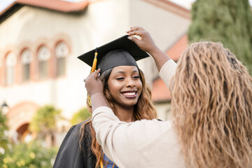 Mother of graduate fixing cap on daughter