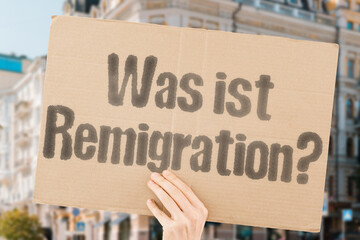"Was ist Remigration?" on a cardboard banner. deportation. policy. controversy. far-right. migration. protest. debate