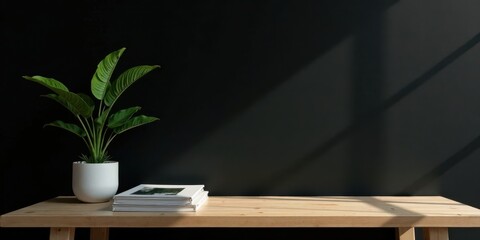 Minimalist home office scene with plant and books on wooden desk against dark wall