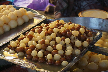 Popular Bangladeshi dessert Gulab Jamun with sugar syrup, Traditional Bangladeshi sweet called rasgulla or rasgoola is being sold at a market, Gulab jamun and rasgulla are displayed together