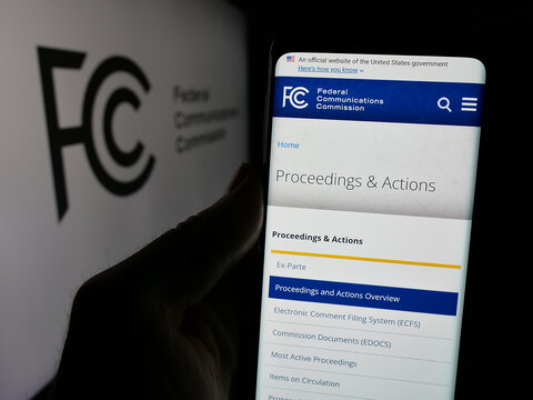 Stuttgart, Germany - 01-23-2025: Person holding cellphone with webpage of US agency Federal Communications Commission (FCC) on screen with logo. Focus on center of phone display.