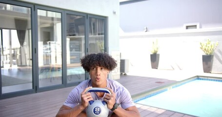 Exercising outdoors, man lifting 8 kg kettlebell by poolside, focusing on fitness - Powered by Adobe