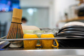 Ceramic cup, dish and bamboo matcha tea whisks on coffee machine at coffee shop.