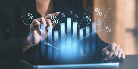 Business professional analyzing glowing bar and line charts with percentages on a virtual screen.