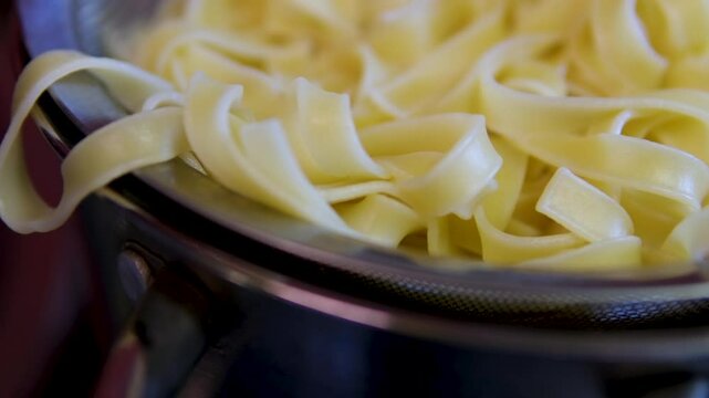 cooked boiled cook Wide egg noodles pappardelle pasta, rotation in circle. handmade pasta, Turning. selective focus 