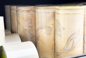 Rolled beige wallpaper with intricate patterns in store display