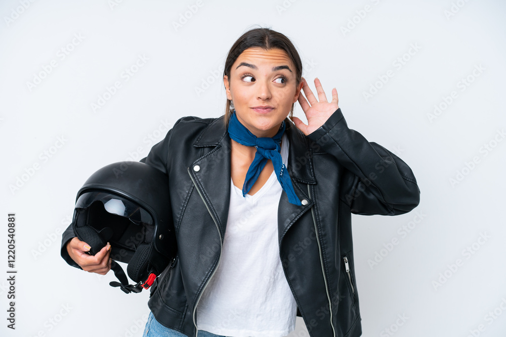 Poster Young caucasian woman with a motorcycle helmet isolated on blue background listening to something by putting hand on the ear