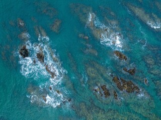 High-angle view of turquoise ocean waves crashing over rocks. Tranquil coastal scene. MAHINEPUA PENINSULA, NORTHLAND, NZ