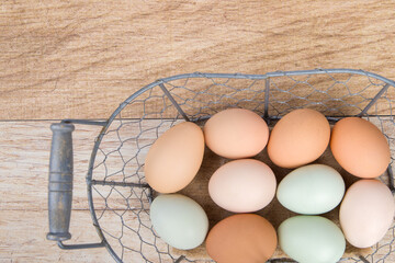 Eggs in a metal basket on a wooden background. Top view.
