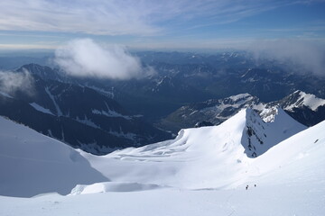 A stunning rock formation covered in snow, set against a clear blue sky with fluffy clouds in the...