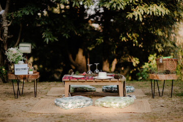 Romantic outdoor picnic setting with a wooden table, floral arrangement, and cozy cushions. Perfect...