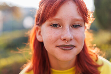 Young beautiful smiling girl with piercing on her face in fashionable clothes. Carefree woman...