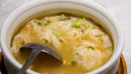 Obraz premium Pancit Molo, a classic Ilonggo soup with dumplings, shredded chicken, and a rich savory broth, served hot at a restaurant in Iloilo, Philippines—comfort food at its finest.
