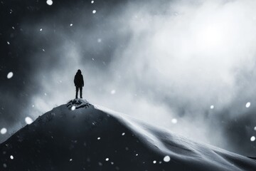 Silhouette of a lone figure standing atop a snow-covered mountain peak during a blizzard.