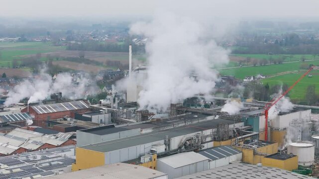 industrial factory oudegem belgium steam chimneys smoke activity associated recycling close up forward aerial drone shot view vpk packaging group 