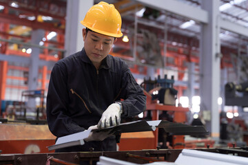 Metalwork manufacturing, warehouse of raw materials. Asian male factory worker inspecting parts of galvanized or metal sheet on conveyor at production line