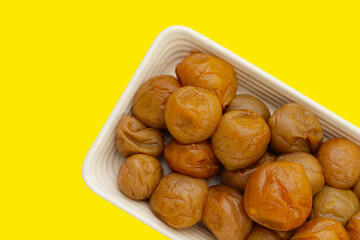 Pickled plums on yellow background.