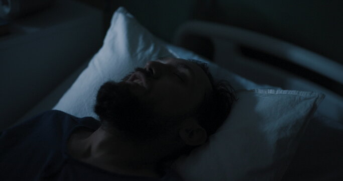 In a hospital room, a troubled-looking guy with disheveled hair screams out loud.