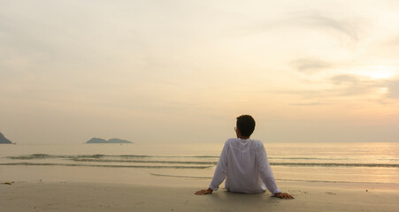 alone man sitting on the beach and looking sky at sunset, relax concept