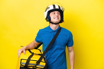 Young Brazilian man with thermal backpack isolated on yellow background thinking an idea while looking up
