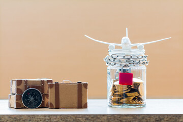Plane model put on the jar bank wallet and luggage put on the desk in the office for saving money for budget with travel planning concept.