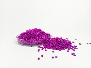 Pink masterbatch plastic granules, polymer carries pigment in a glass cup poured with a white...