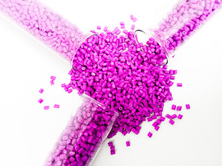 Pink masterbatch plastic granules, polymer carries pigment in glass tube poured with white background, suitable for product catalog design of plastic manufacturing industry company profile
