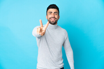 Fototapeta premium Caucasian man over isolated blue background smiling and showing victory sign