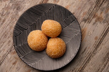 onde-onde or sesame balls are sweet snacks filled with green beans. sesame balls on a black ceramic plate.