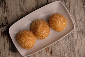onde-onde or sesame balls are sweet snacks filled with green beans. sesame balls on a white ceramic plate.